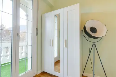 a room with a large window and a fan on a tripod at Penthouse Jolanda Meran-o in Merano