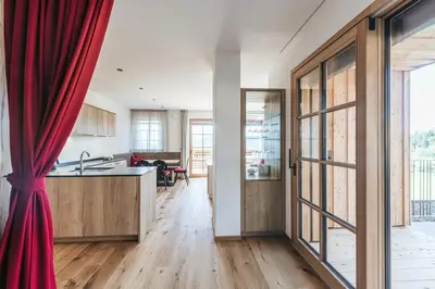 a kitchen with wooden floors and a red curtain at Lochbauer in Meltina