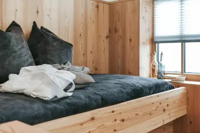 a bed in a room with wooden walls and a window at Lochbauer in Meltina