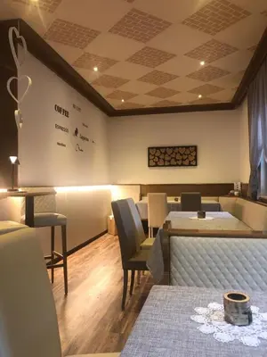 a waiting room with tables and chairs and a white wall at Albergo Bernard in Canazei