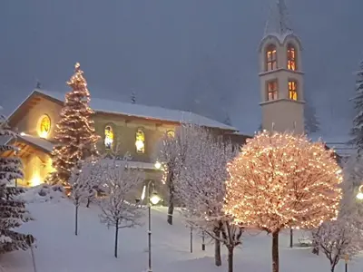 a building with a christmas tree and a clock tower at Albergo Bernard in Canazei