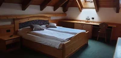 a bedroom with a wooden bed and a desk at Albergo Bernard in Canazei