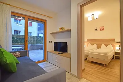 a living room with a bed and a television in a room at Vacanze Arcobaleno in Predazzo