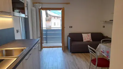 a kitchen and a living room with a couch at Vacanze Arcobaleno in Predazzo