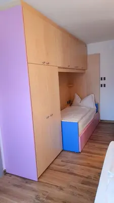 a small bedroom with a bed and cabinets at Vacanze Arcobaleno in Predazzo