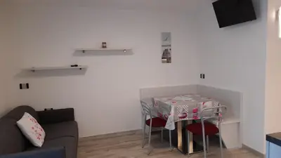 a living room with a table with chairs and a couch at Vacanze Arcobaleno in Predazzo