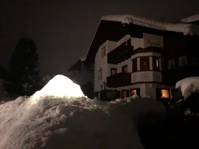 a yard covered in snow at night with lights at Appartamenti Hacoli in Selva di Val Gardena