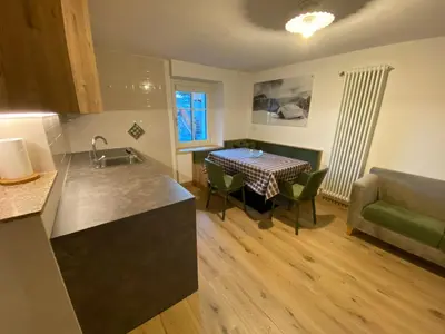 a kitchen and living room with a table and a couch at Casa Dorich in Pozza di Fassa
