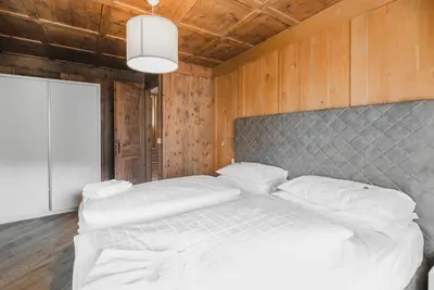 a bedroom with two white beds and a wooden wall at Casa Dorich in Pozza di Fassa