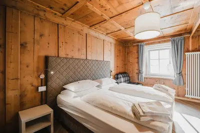 a bedroom with a bed in a room with wooden walls at Casa Dorich in Pozza di Fassa