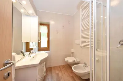 a white bathroom with a sink and a toilet at Casa Dorich in Pozza di Fassa