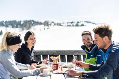 a group of people sitting around a table eating food at Ariala Apartments in Falzes