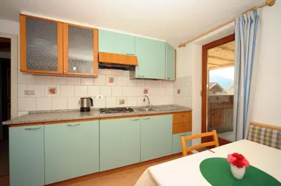 a kitchen with blue cabinets and a table with a vase at Oberpiskoihof in Funes