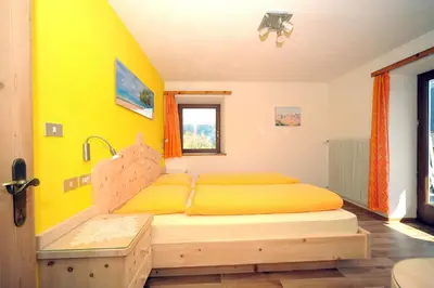 a bedroom with a bed with a yellow wall at Oberpiskoihof in Funes