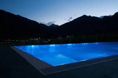 a blue swimming pool with mountains in the background at Hotel Pacherhof in Bressanone