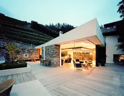 a house with a deck with a stone wall at Hotel Pacherhof in Bressanone