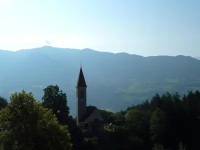 a church on top of a hill with trees at Gasthof Weidmannshof in Bressanone
