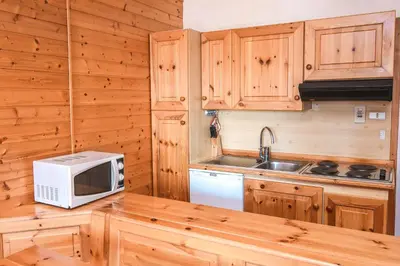a kitchen with wooden cabinets and a microwave at Appartamenti Dolomiti con piscina e sauna in Cavalese