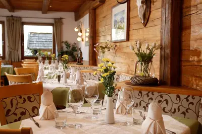 a dining room with a table with wine glasses and flowers at Hotel Hubertusstube in Laion