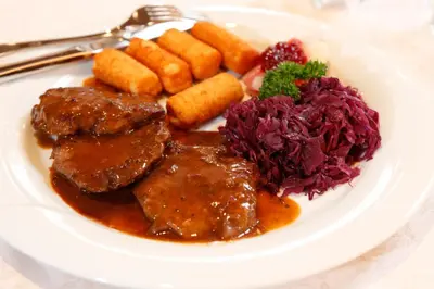 a plate of food with meat and vegetables on a table at Hotel Hubertusstube in Laion