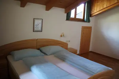 a bedroom with a bed with blue sheets and a window at Blummerhof in Lagundo