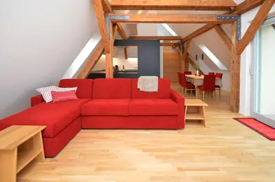 a red couch in a living room with a table at Aurturist Brunico in Brunico