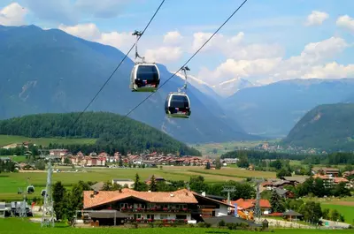 a couple of cable cars flying over a village at Aurturist Brunico in Brunico