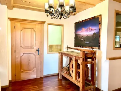 a living room with a chandelier and a table with a tv at Chalet Bernardi Apartments in Ortisei