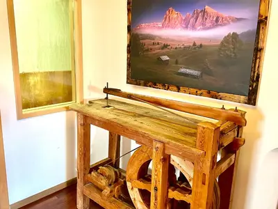 a painting hanging on a wall next to a wooden table at Chalet Bernardi Apartments in Ortisei