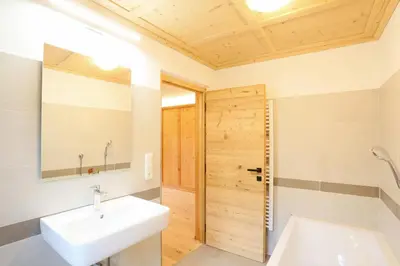 a bathroom with a white sink and a wooden door at Hanslerhof in Braies