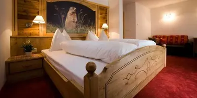 a bedroom with a large bed with white sheets at Hotel Pfandleralm in San Martino