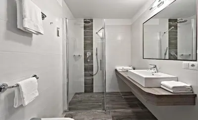 a white bathroom with a sink and a shower at Hotel Pfandleralm in San Martino