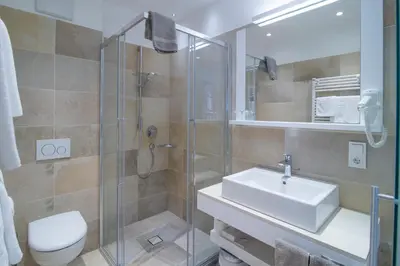 a bathroom with a shower and a sink and a toilet at Garni Hotel Kessler in Tirolo