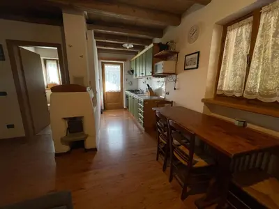 a kitchen with a wooden table and a wooden floor at Agriturismo Maso Fumas in Canale dʼAgordo