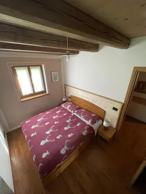 a bedroom with a bed with a purple comforter and a window at Agriturismo Maso Fumas in Canale dʼAgordo