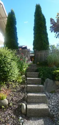 a set of stone stairs in a garden with two trees at Haus Schönblick in San Lorenzo di Sebato