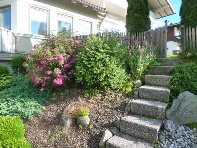 a garden with rocks and flowers in front of a house at Haus Schönblick in San Lorenzo di Sebato