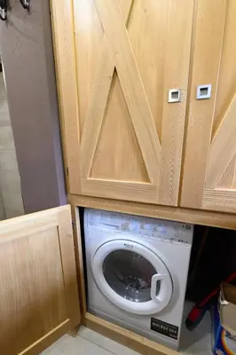a washing machine in a kitchen with wooden cabinets at Casa Ladinia in San Vito di Cadore