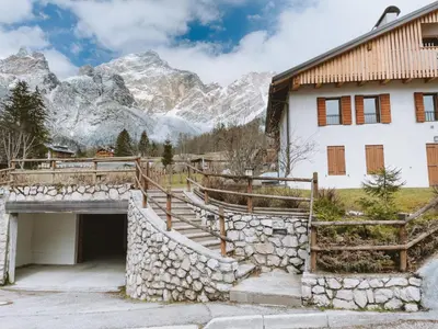 a building with a ramp leading to a garage and mountains at Casa Ladinia in San Vito di Cadore