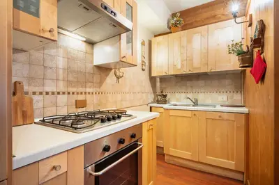a kitchen with wooden cabinets and a stove top oven at Villa S. Francesco - Stayincortina in Cortina dʼAmpezzo