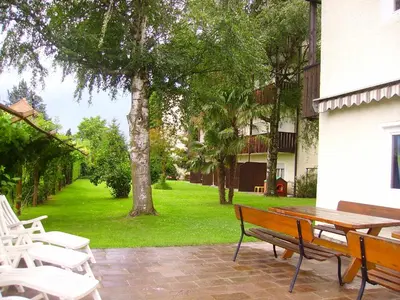 a park with a wooden bench next to a building at Residence Bichler in Merano