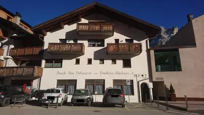 a building with red flowers on the side of it at Residence Ploner in San Cassiano