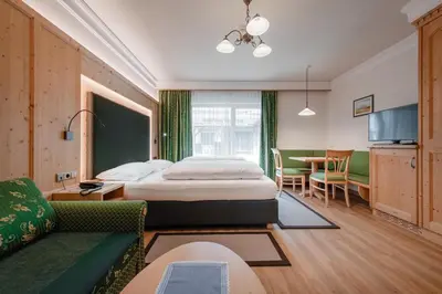 a hotel room with a bed and a dining room at Hotel Sureghes in Ortisei