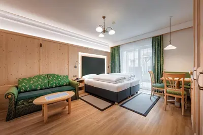 a bedroom with a bed and a couch and a table at Hotel Sureghes in Ortisei