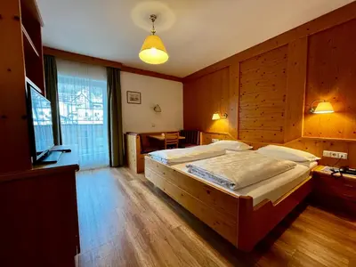a bedroom with a large bed and a table at Hotel Sureghes in Ortisei