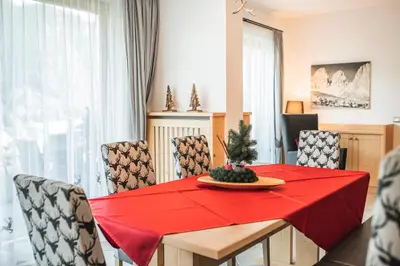 a dining room with a red table with chairs at Chalet Residence Alpinflair in Ortisei