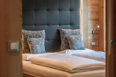 a large bed with a blue headboard and pillows at Chalet Residence Alpinflair in Ortisei