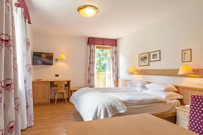 a bedroom with two beds and a desk at Hotel Malga Passerella in Moena