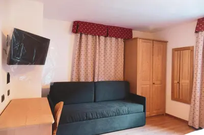a living room with a green couch and a cabinet at Hotel Malga Passerella in Moena