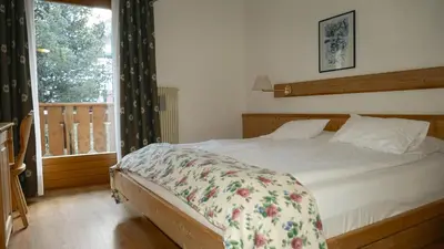 a bedroom with a bed with a floral blanket on it at Hotel Malga Passerella in Moena